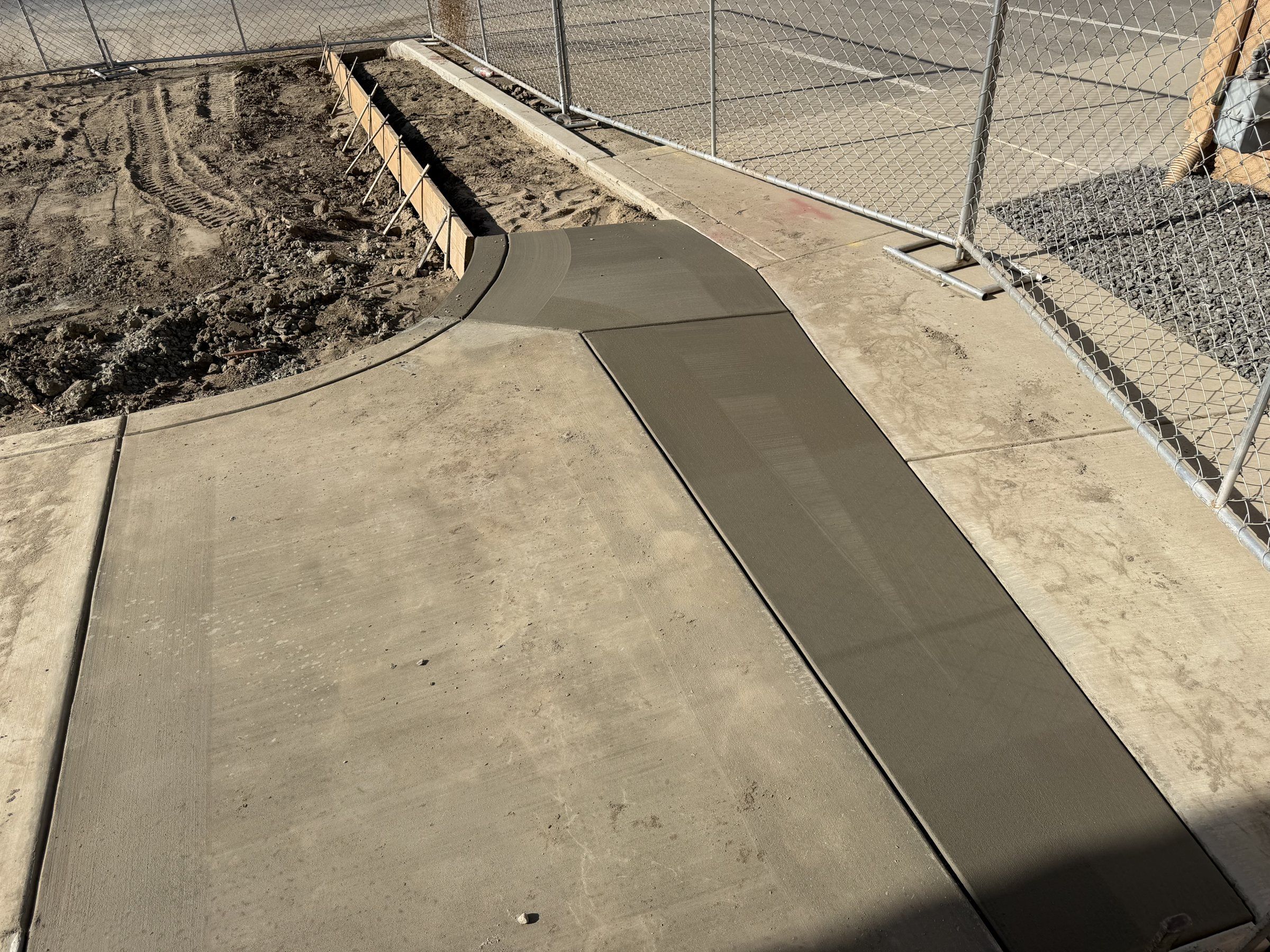 New concrete sidewalk with a formed edge along a fence line
