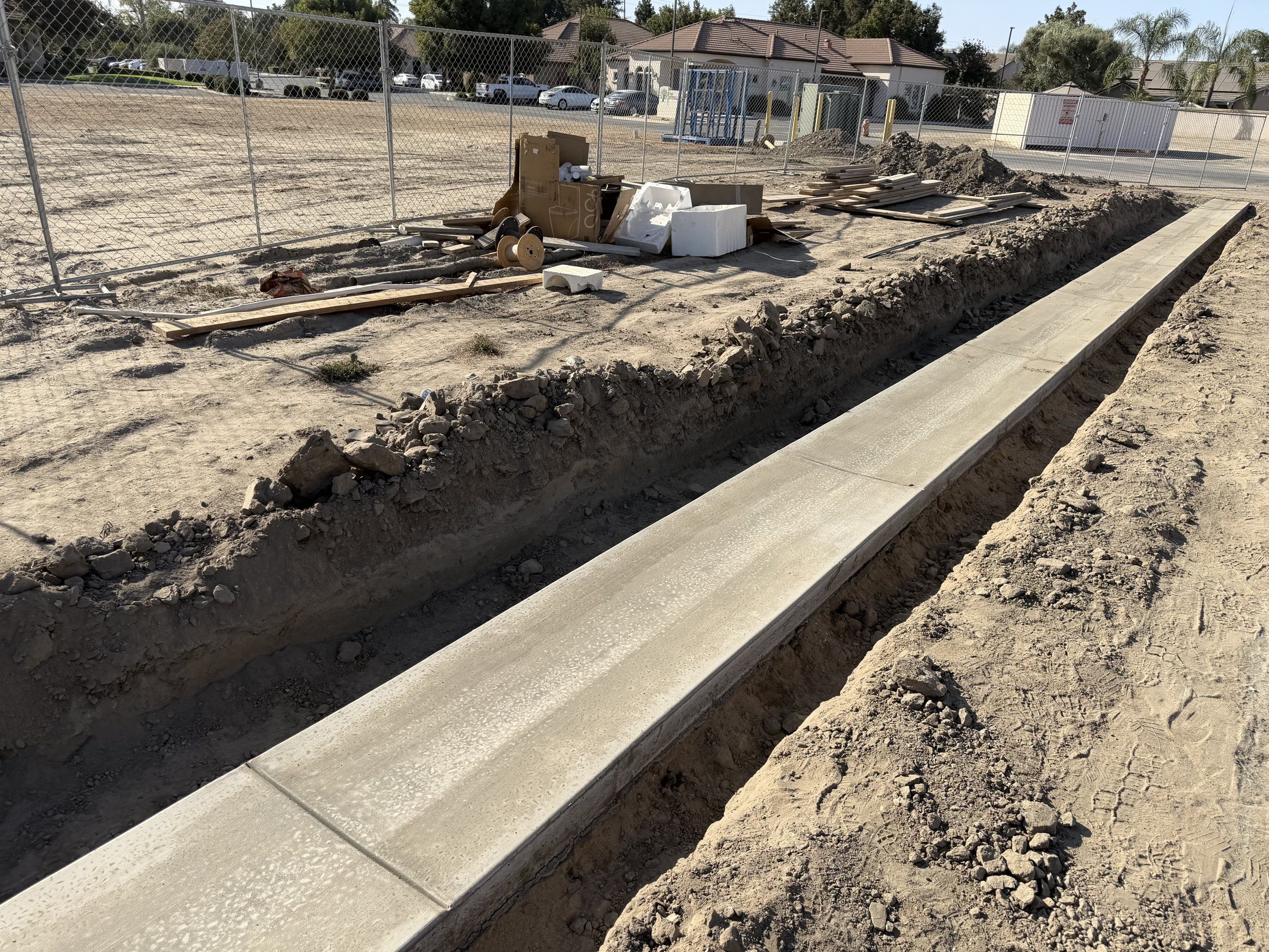 Straight concrete curb poured along an open trench