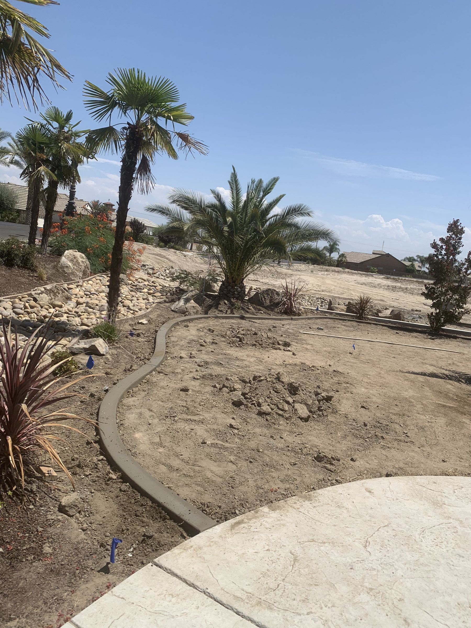 Curved concrete landscape curb between gravel and a walkway