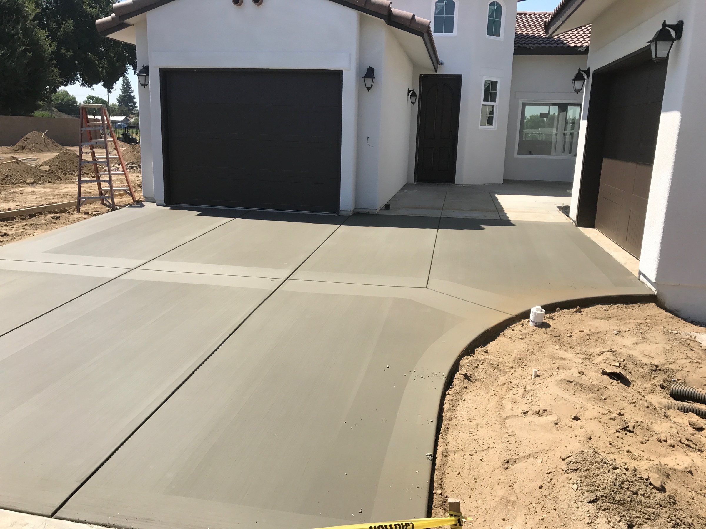 New broom-finish concrete driveway with saw-cut joints in front of a two-car garage