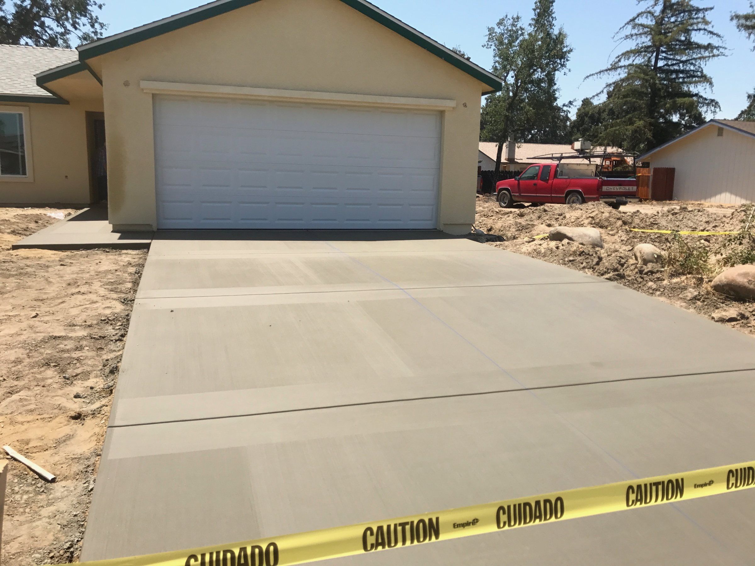 Freshly poured concrete driveway leading to a white garage door