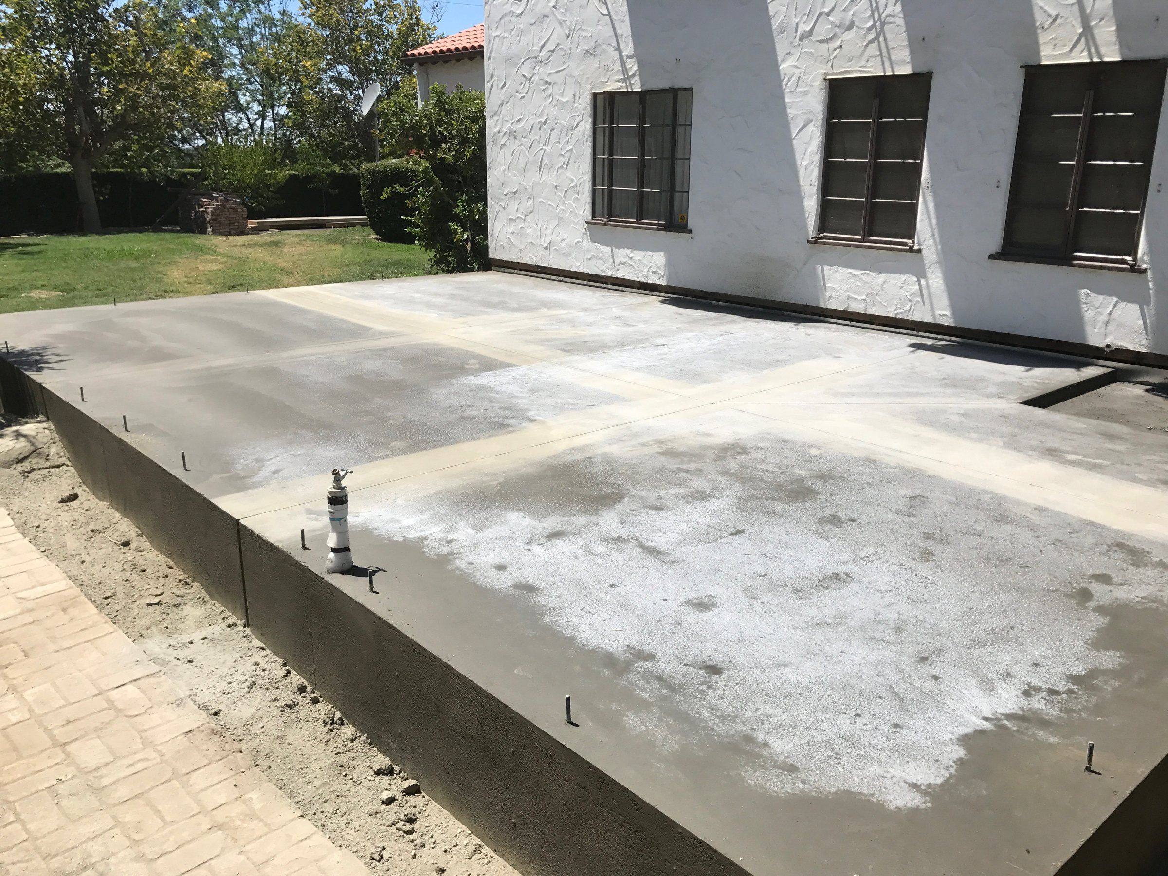 Raised concrete patio slab along the side of a stucco house