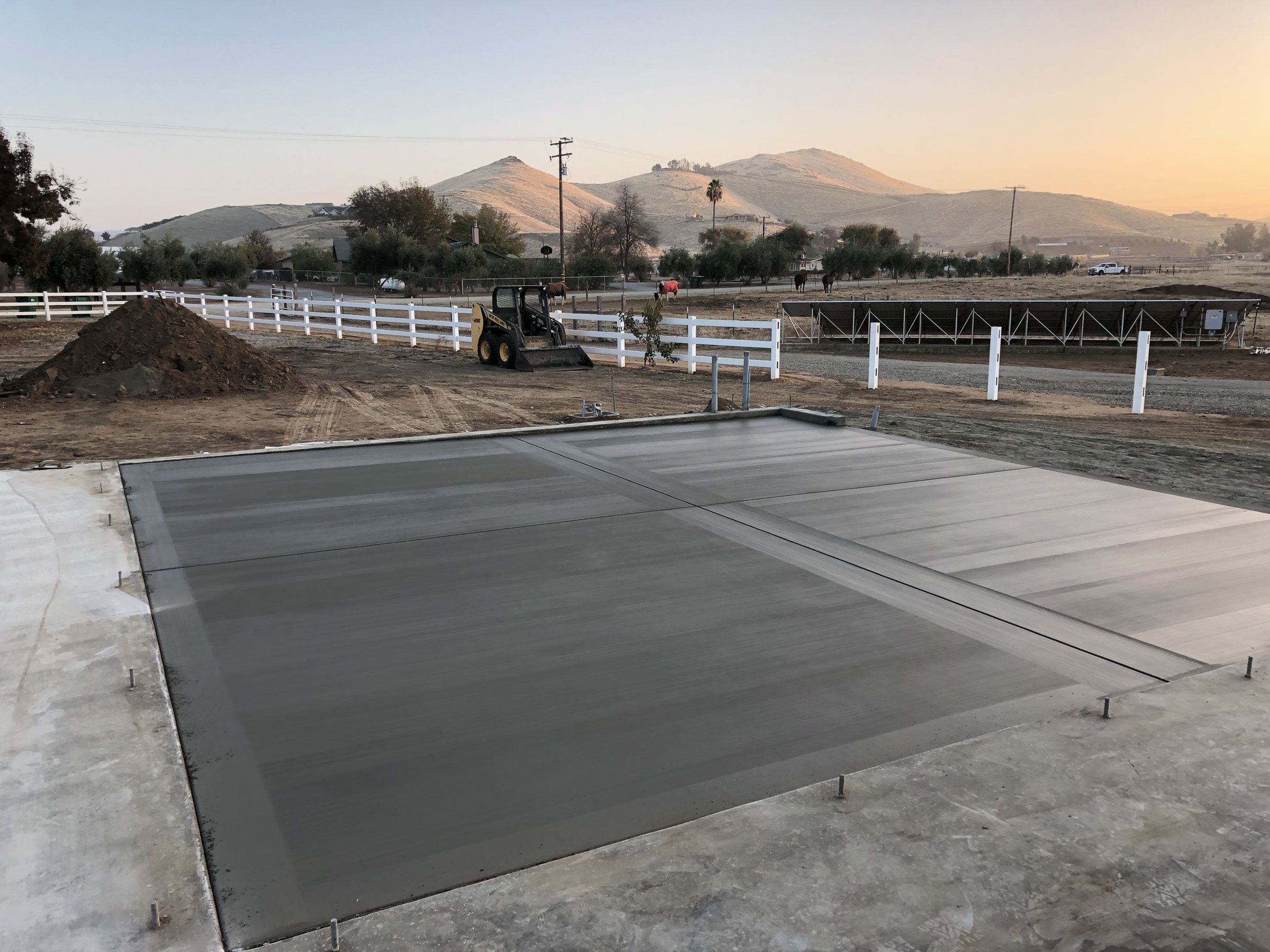 Large concrete pad with trowel borders on open land with hills behind