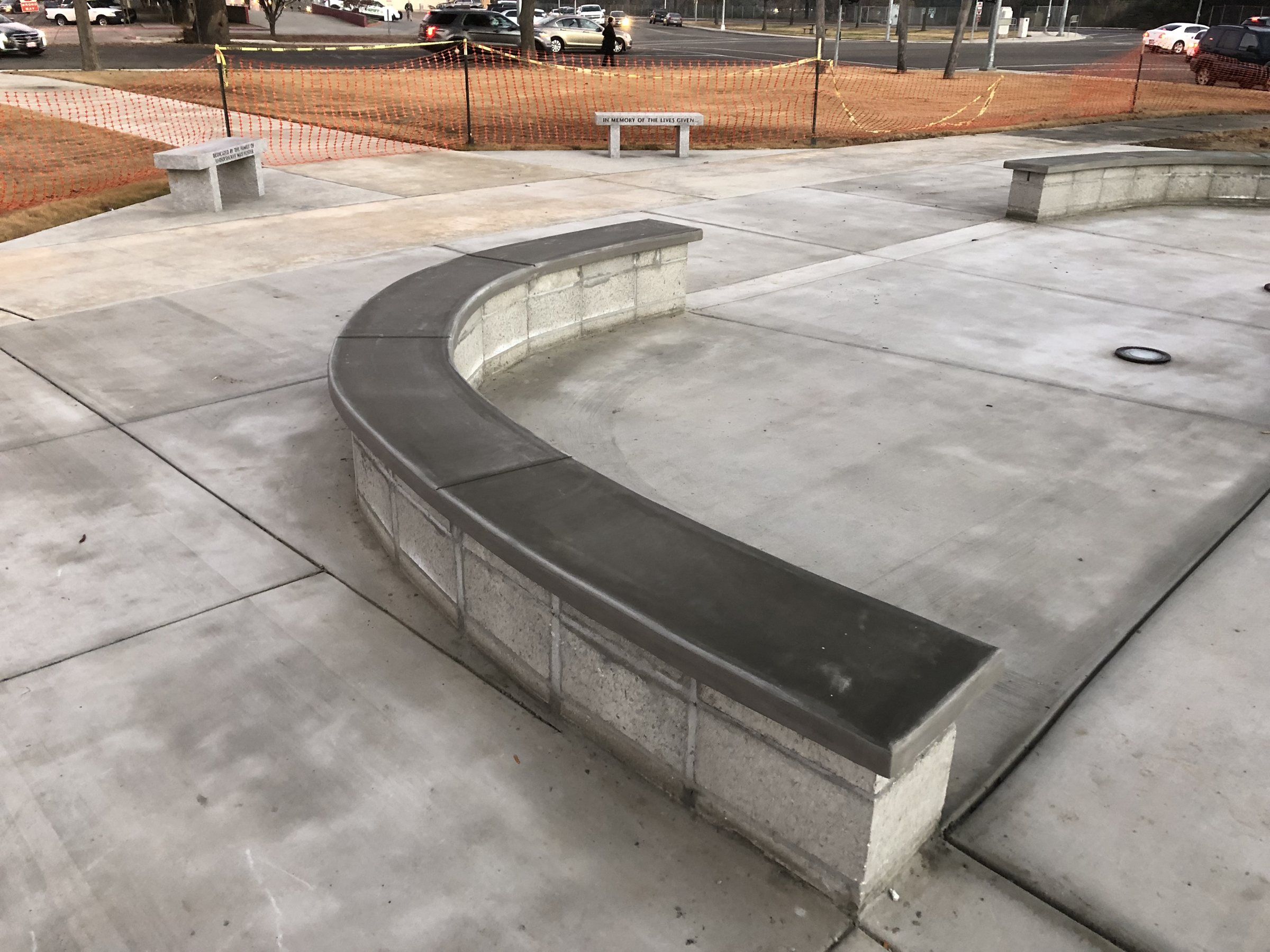 Curved concrete seat wall with a smooth cap on a large concrete plaza