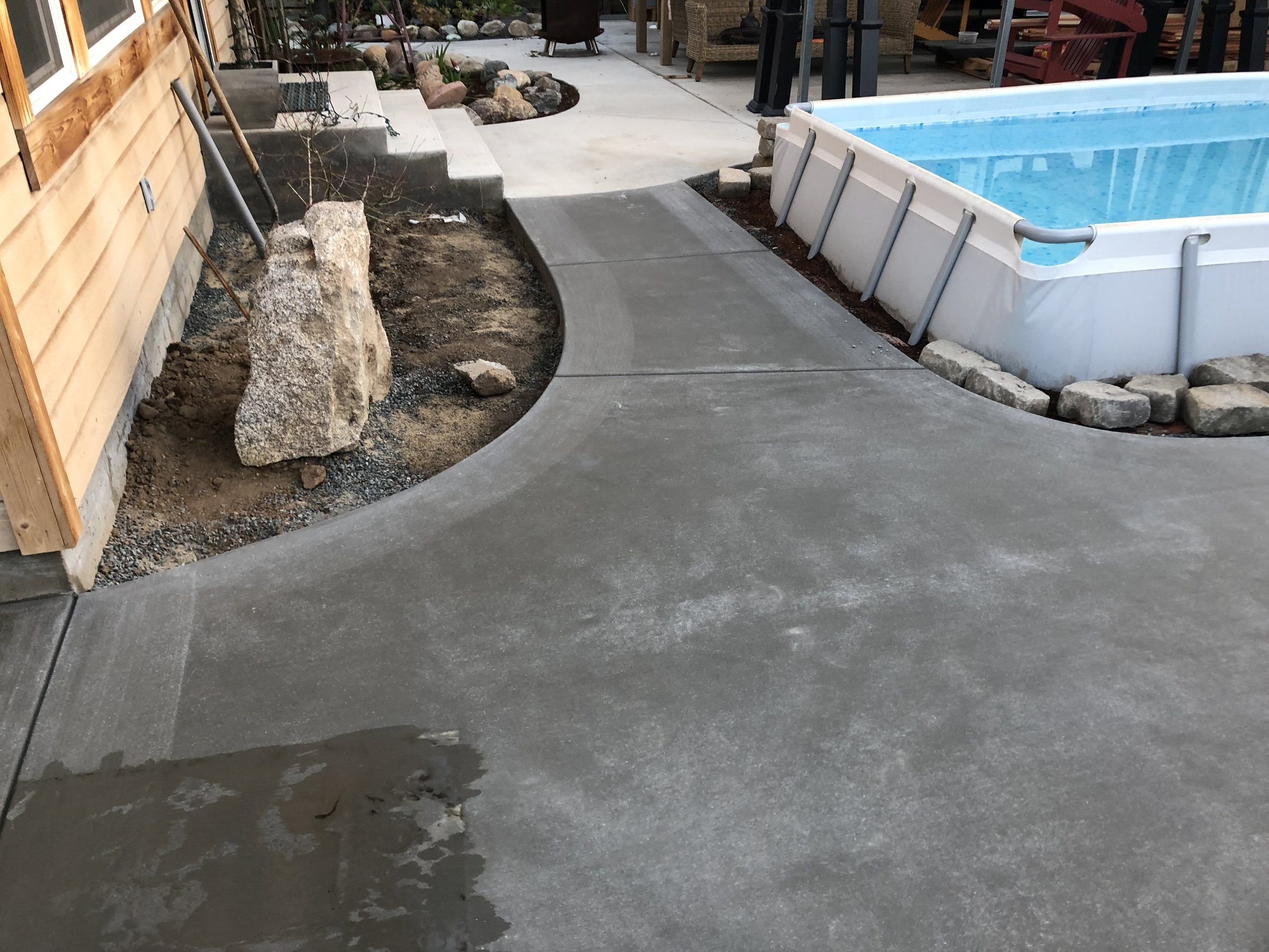 Curved concrete side yard walkway next to an above-ground pool