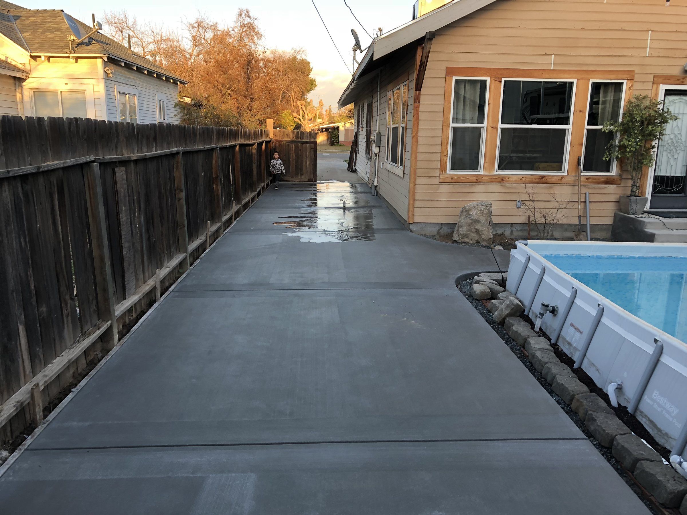 Long concrete side yard walkway between a fence and a house