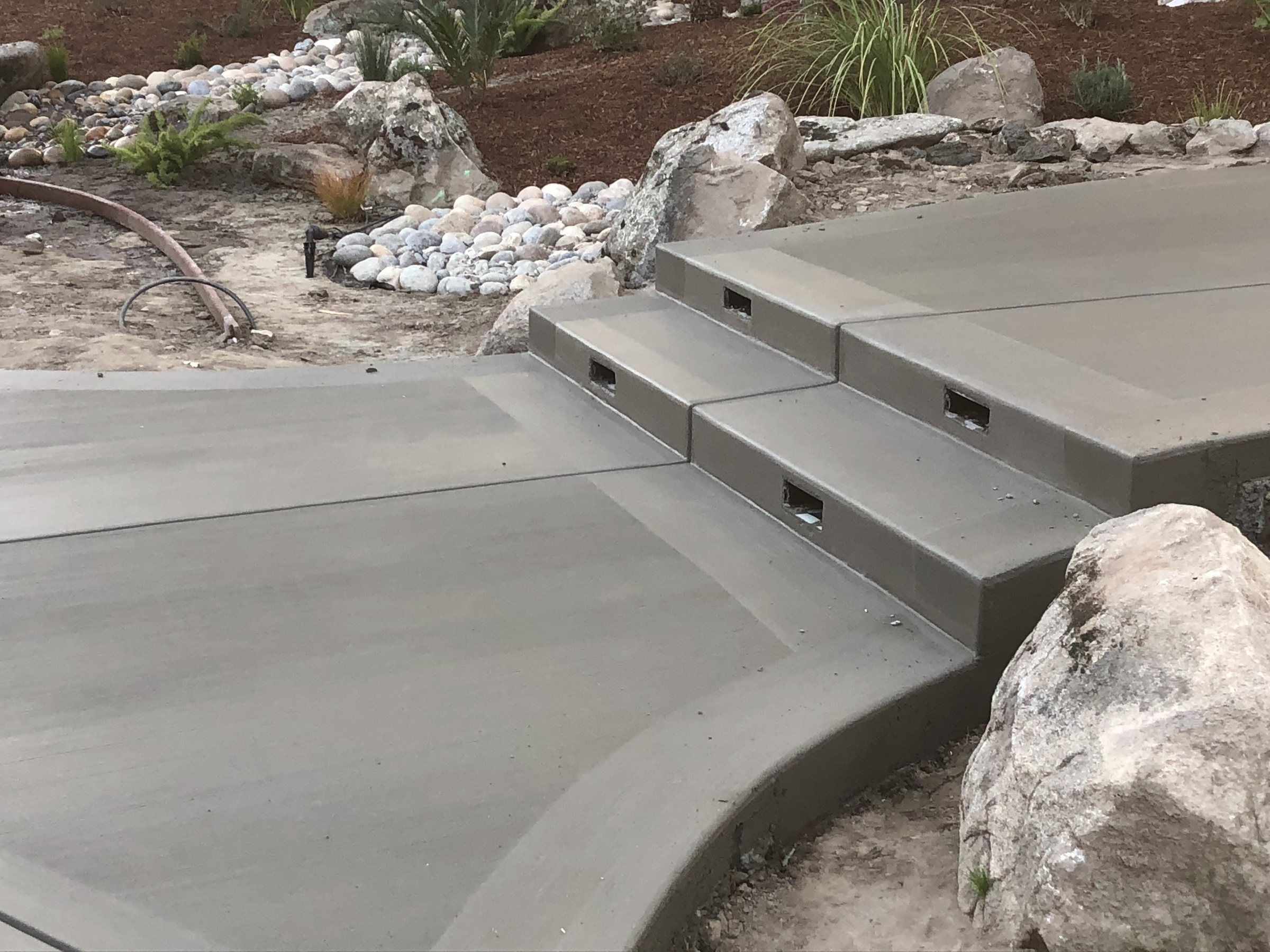 Concrete patio and steps set among landscape boulders