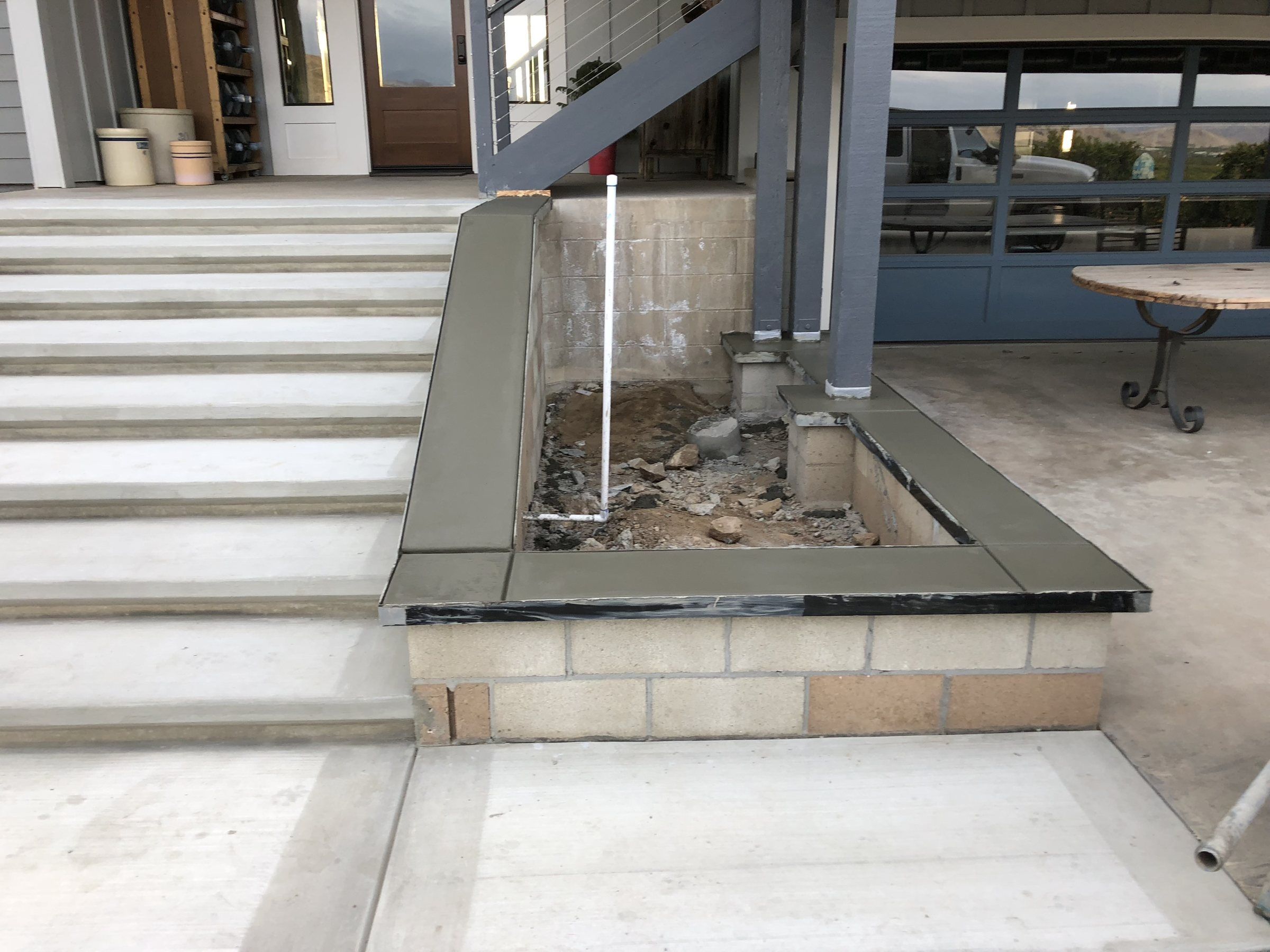 Concrete steps and a planter cap at a covered patio