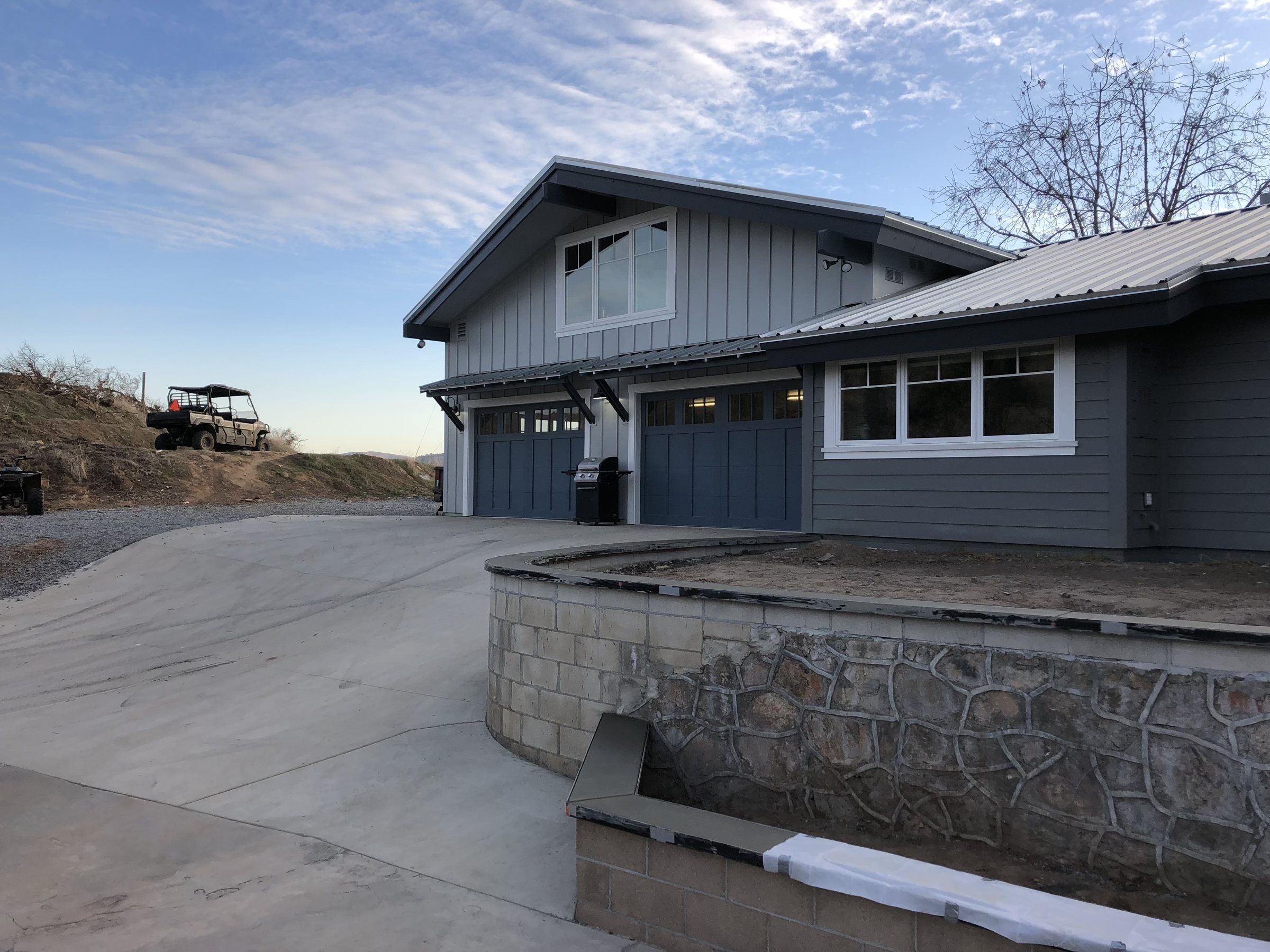Concrete driveway approach and retaining wall cap at a two-story house