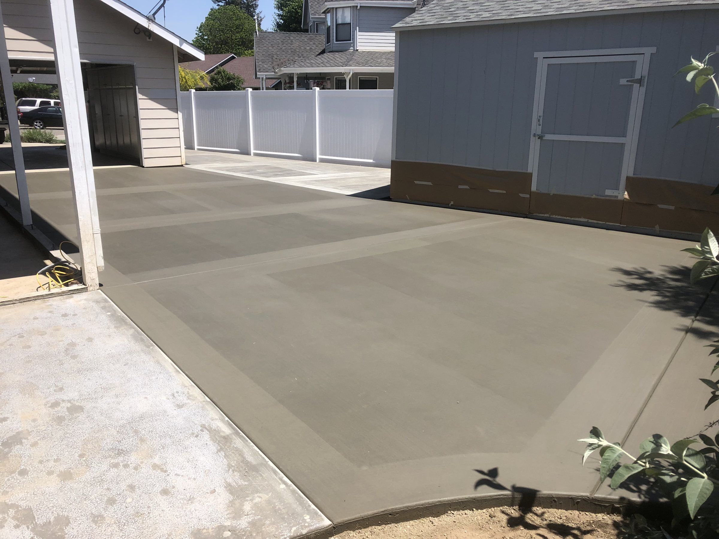 Concrete pad with a smooth border poured beside a backyard shed