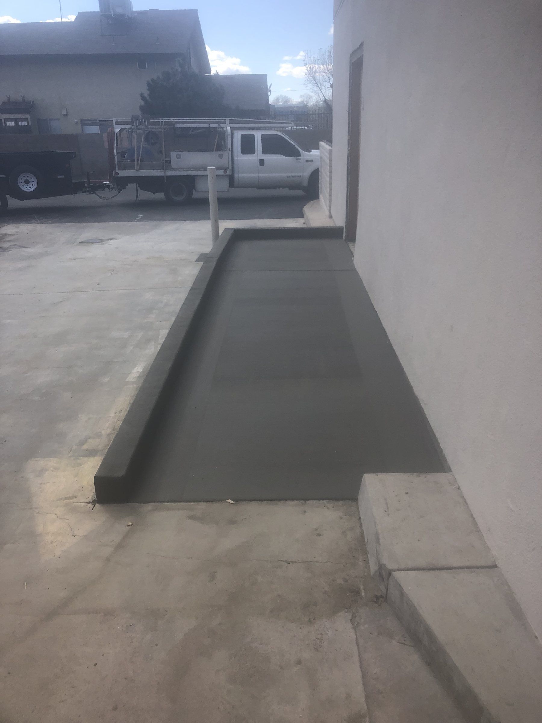 Dark-toned concrete strip with a raised edge along the side of a house