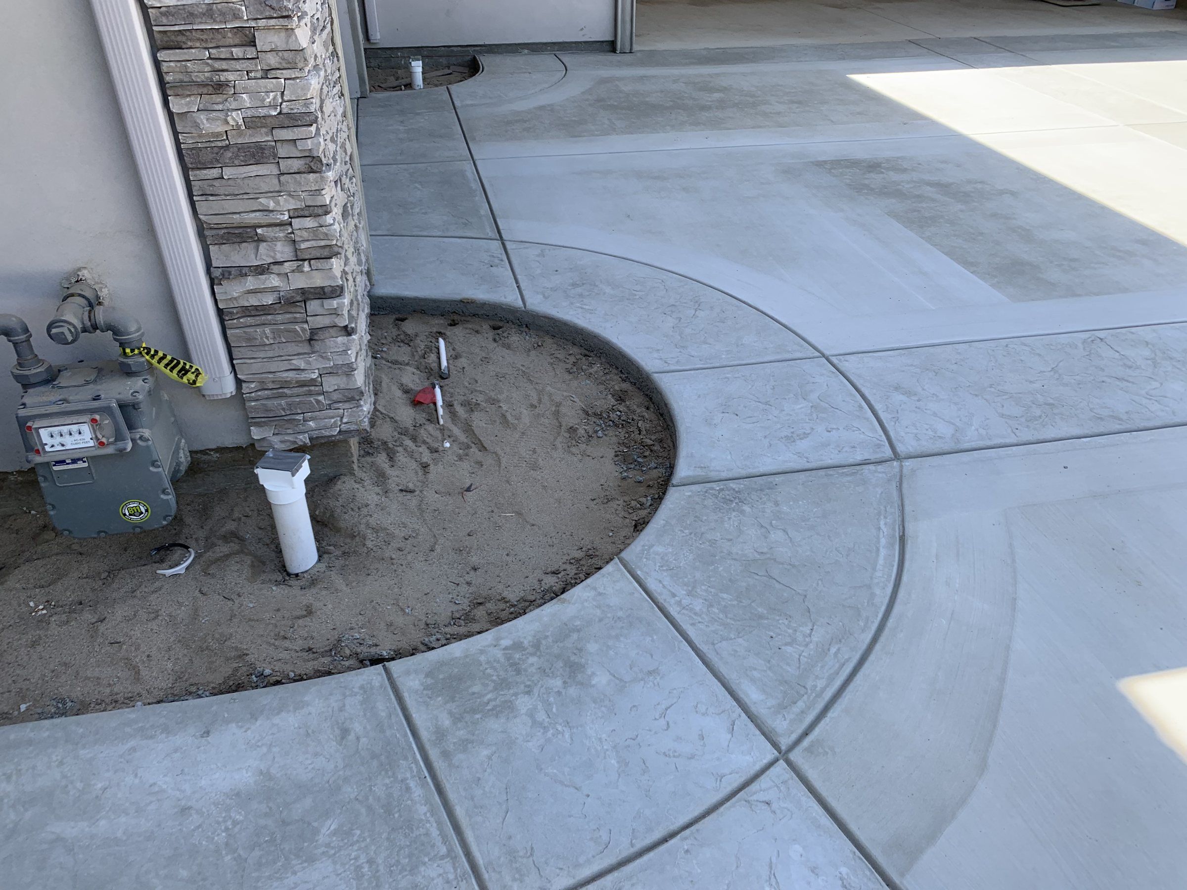 Concrete walkway with curved border bands cut around a planter